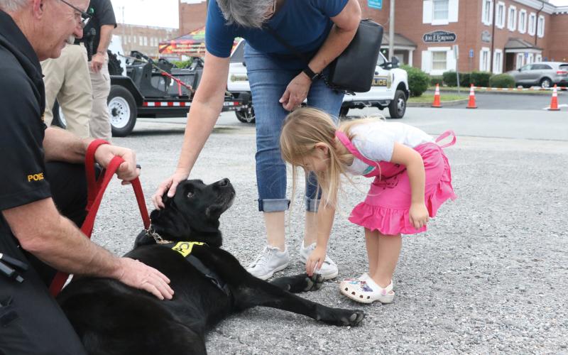 Maddie Boone (right) goes in for a pet on Fresca, an accelerant detection K9 that helps investigate cases of arson, during last year’s National Night Out event. (FILE)