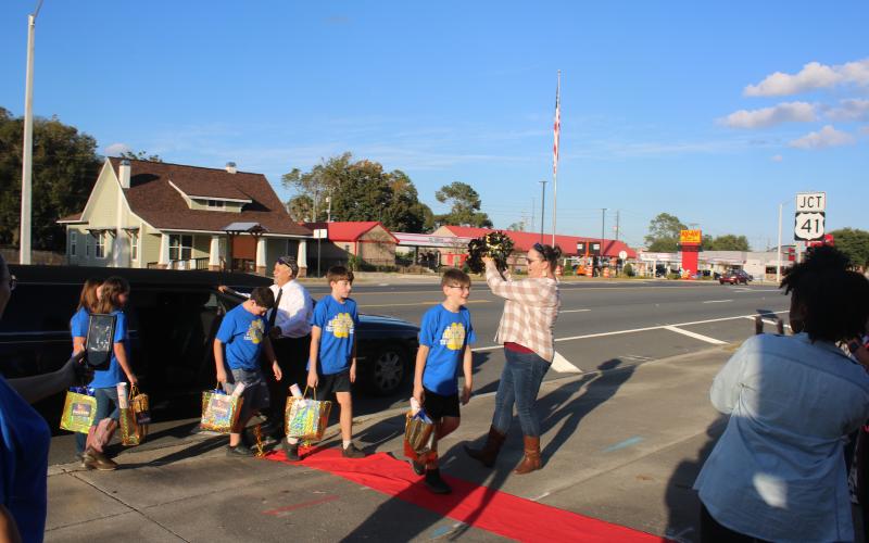 Brandon Ruwe (foreground) is greeted by Sarah Ripple, an Eastside Elementary School third-grade teacher, as he and Andrew Howard, Ryan McDaniel, Kendalynn Coates and Chloe Felton exit a limousine before Tuesday evening’s school board meeting. (TONY BRITT/Lake City Reporter)