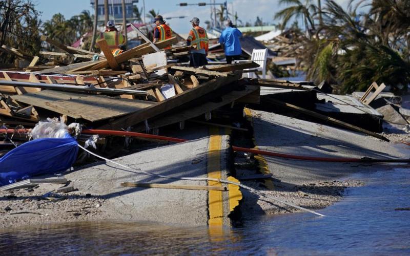 Responders from the de Moya Group survey damage to the bridge leading to Pine Island to start building temporary access to the island in the aftermath of Hurricane Ian on Sunday in Matlacha. The only bridge to the island is heavily damaged so it can only be reached by boat or air. (GERALD HERBERT/Associated Press)