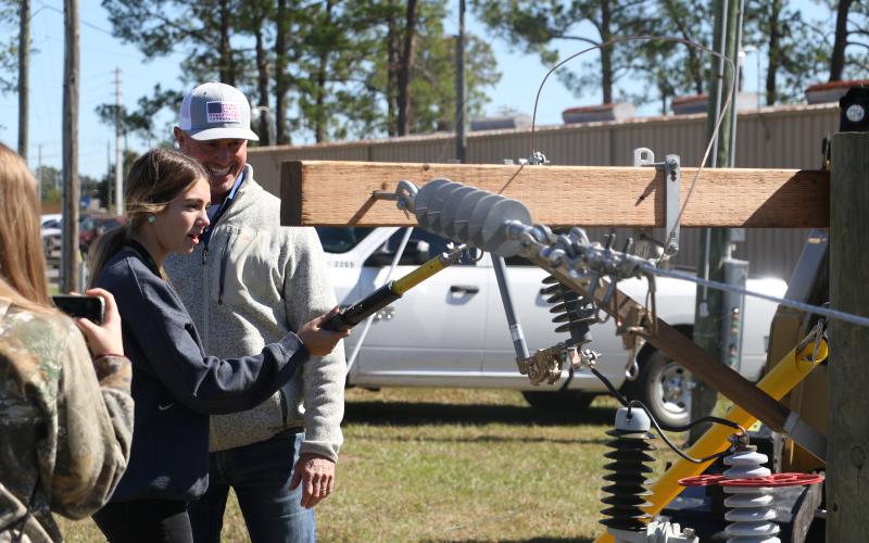 Mackenzie Thomas, a Columbia High School sophomore, learns the proper technique for handling electrical equipment at the Clay Electric Cooperative booth Wednesday morning. (MORGAN MCMULLEN/Lake City Reporter)