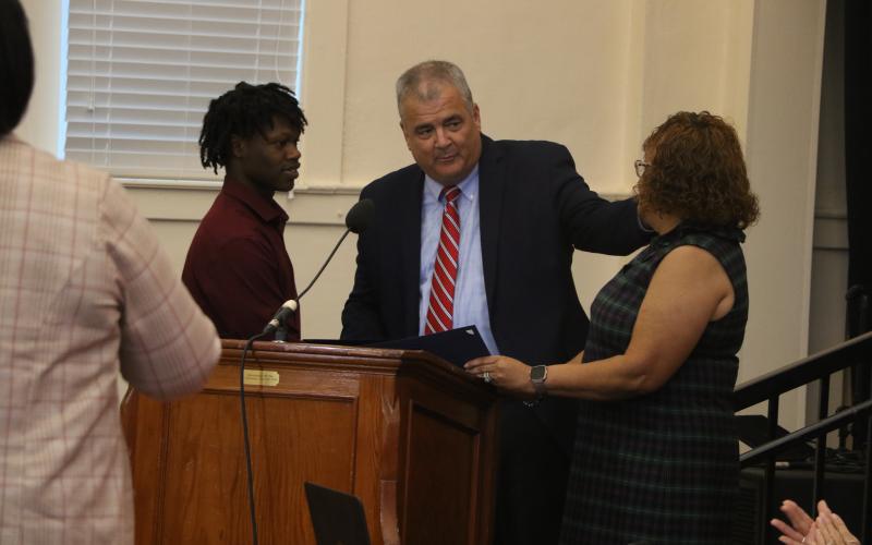 Fort White High School senior Khambrell White (left) is presented a certificate of appreciation by Columbia Schools Superintendent Lex Carswell (middle) and Columbia School Board Chair Narrie Smith on Monday for his actions in helping reunite a dementia patient with her family. (MORGAN MCMULLEN/Lake City Reporter)