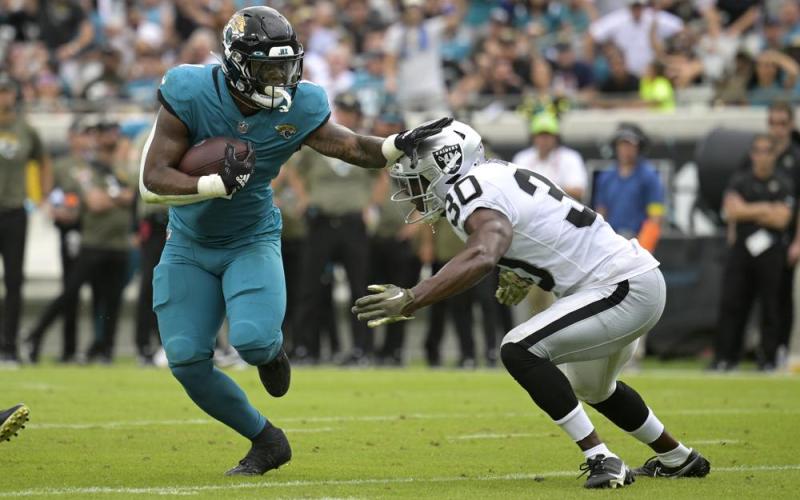 Jacksonville Jaguars running back Travis Etienne Jr. tries to get past Las Vegas Raiders safety Duron Harmon during Sunday's game in Jacksonville. (PHELAN M. EBENHACK/Associated Press)