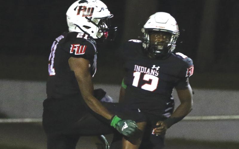Fort White running back Najeeb Smith (12) celebrates with teammate Kamarion Griffin after scoring a touchdown against Santa Fe last Friday. (MORGAN MCMULLEN/Lake City Reporter)