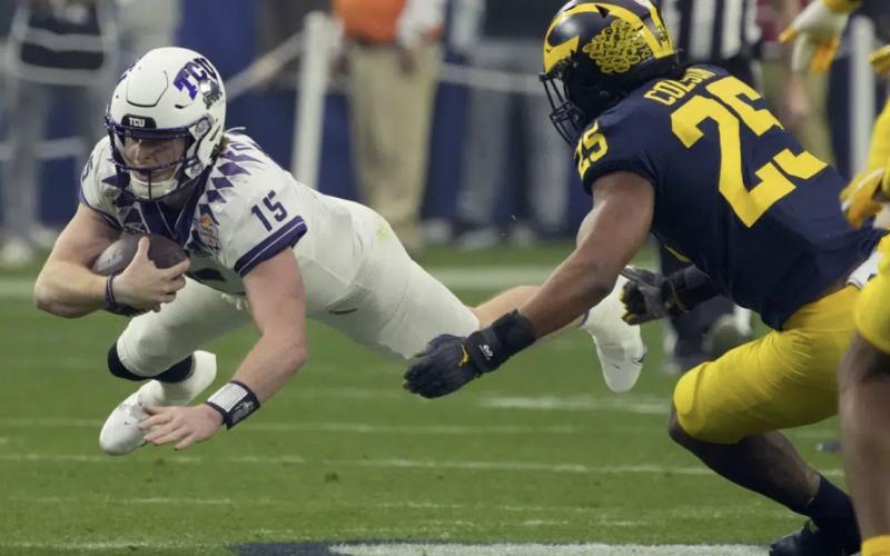 TCU quarterback Max Duggan (15) dives for yardage as Michigan linebacker Junior Colson (25) defends the Fiesta Bowl playoff semifinal on Saturday in Glendale, Ariz. (RICK SCUTERI/Associated Press)