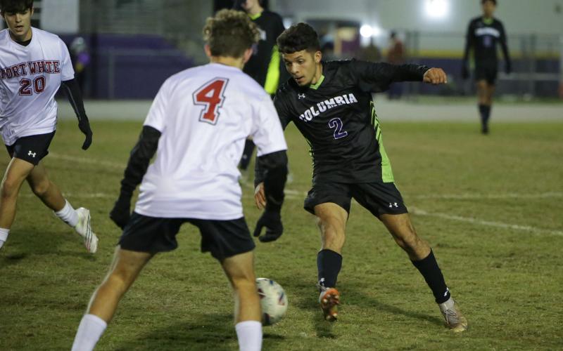 Columbia’s Jason Caballero dribbles up the field against Fort White’s Gavin Heaton on Monday night. (BRENT KUYKENDALL/Lake City Reporter)