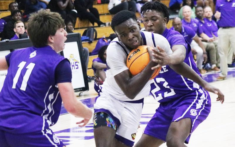Columbia guard Isaac Broxey tries to drive past Gainesville’s Seth Childers (11) and Jordan Bodie (23) on Thursday night. (JORDAN KROEGER/Lake City Reporter)