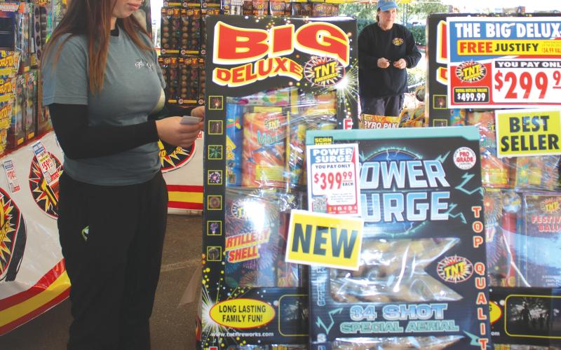 Kenzie Dungan, a Columbia High School FFA member, places pricing stickers on firework displays in the Columbia High School FFA fireworks tent on Tuesday afternoon. (TONY BRITT/Lake City Reporter)