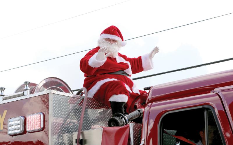 Santa Claus waves atop a firetruck during last year’s Fort White Christmas parade. (FILE)