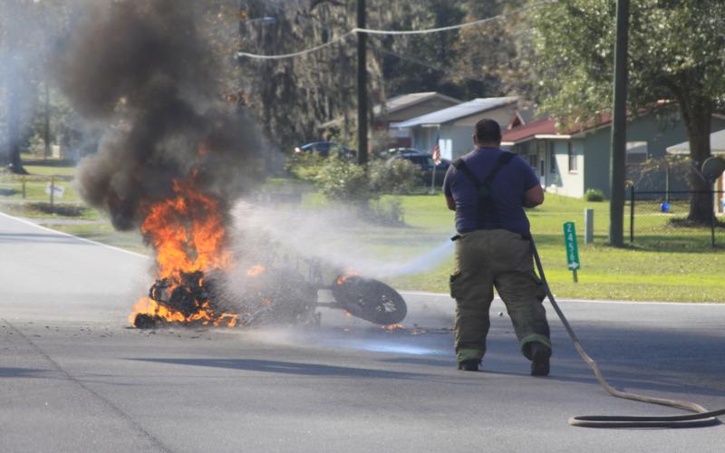 A Columbia County firefighter extinguishes the flames from the motorcycle Tuesday afternoon. (MATTHEW GLOVER/Special to the Reporter)