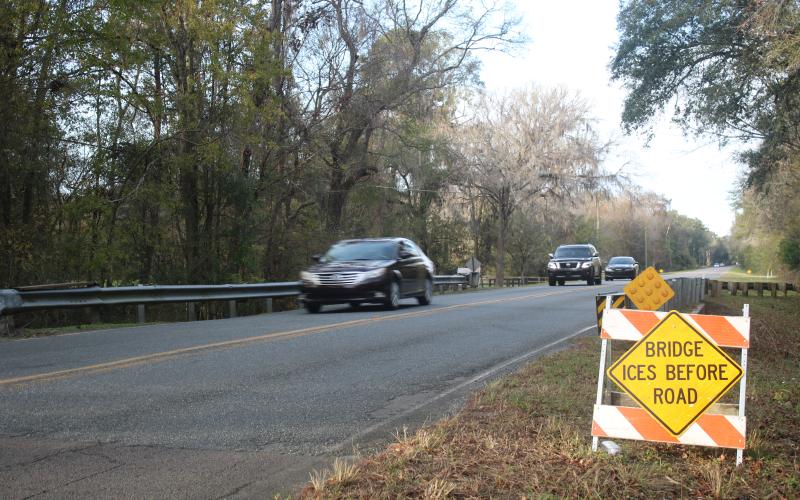 Vehicles travel southbound on Southeast Country Club Road on Thursday afternoon, after county crews erected hazardous conditions signs for both lanes of travel for a local bridge. The signs have been erected at 34 locations across the county. (TONY BRITT/Lake City Reporter)