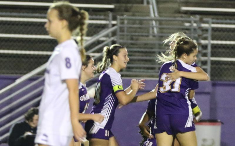 Columbia’s Mia Brasel is embraced by teammates Sydney Rivas (31) and Skyler Ziegaus (left) after her goal as Gainesville’s Emily Brown (8) walks away Wednesday night. (MORGAN MCMULLEN/Lake City Reporter)