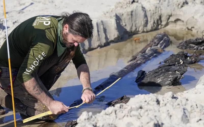 Archaeologist Christopher McCarron takes measurements of a structure exposed in the sand Tuesday in Daytona Beach Shores. (JOHN RAOUX/Associated Press)