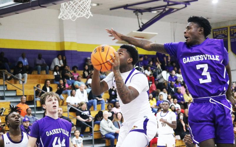 Columbia guard Tray Tolliver rises for a shot as Gainesville’s Theo Stephens attempts to block it on Thursday night. (JORDAN KROEGER/Lake City Reporter)