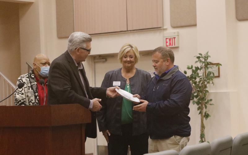David Boozer (left), the Florida Gateway Food Bank Manager, presents a ceremonial plate to Eastside Elementary Principal Roger Little as Catholic Charities Regional Director Suzanne Edwards looks on. (JAMIE WACHTER/Lake City Reporter)
