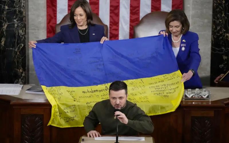 Vice President Kamala Harris and House Speaker Nancy Pelosi of Calif., right, react as Ukrainian President Volodymyr Zelenskyy presents lawmakers with a Ukrainian flag autographed by front-line troops in Bakhmut, in Ukraine's contested Donetsk province, as he addresses a joint meeting of Congress on Capitol Hill in Washington, Wednesday. (JACQUELYN MARTIN/Associated Press)