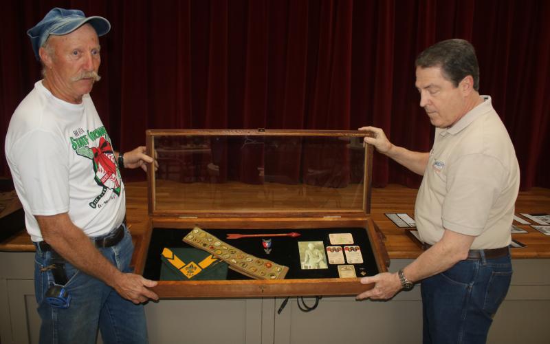 Jay Fraser (from left), local scouting organization representative and Darrel Mathis, Boy Scout Troop 85 Committee Chair, set up a display in the First Presbyterian Church Fellowship Hall that displays scouting memorabilia of Forrest Bradbury, the first Eagle Scout for the group from 1931. A reception will take place Sunday morning in the fellowship hall to celebrate 100 years of local scouting. (TONY BRITT/Lake City Reporter)