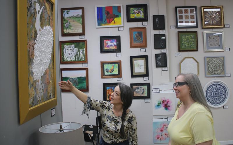 Gateway Art Gallery Curator Sheila Carr (left) points out a work of 3D art to Melanie Thum. (TONY BRITT/Lake City Reporter)