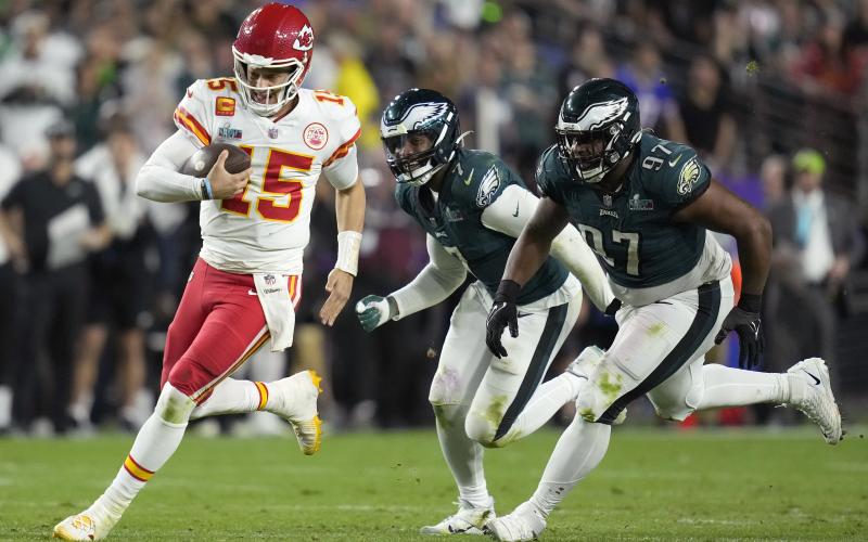 Kansas City Chiefs quarterback Patrick Mahomes runs against Philadelphia Eagles defensive tackle Javon Hargrave (97) and linebacker Haason Reddick (7) during Super Bowl 57 on Sunday in Glendale, Ariz. (ASHLEY LANDIS/Associated Press)