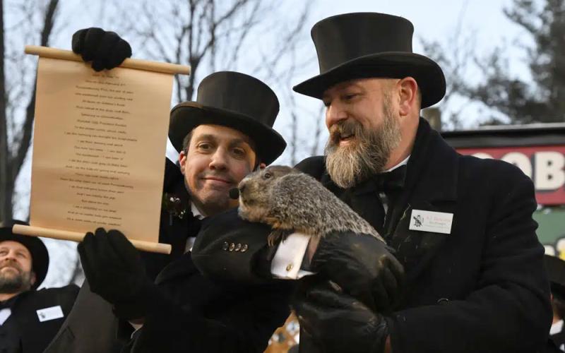 Groundhog Club handler A.J. Dereume holds Punxsutawney Phil, the weather prognosticating groundhog, while Vice President Dan McGinley reads the scroll during the 137th celebration of Groundhog Day on Gobbler’s Knob in Punxsutawney, Pa. (BARRY REEGER/Associated Press)