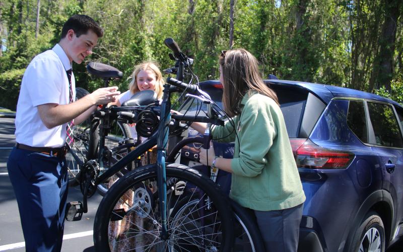 Elder Carter Snow (from left) helps Sisters Kimberlie Palmer and Tara Wallace secure their bikes on a bicycle rack on Thursday afternoon in the Church of Jesus Christ of Latter Day Saints parking lot on Old Country Club Road. The missionaries were taking part in Transfer Day where they were pairing-up with new companions to conduct their mission work. (TONY BRITT/Lake City Reporter)