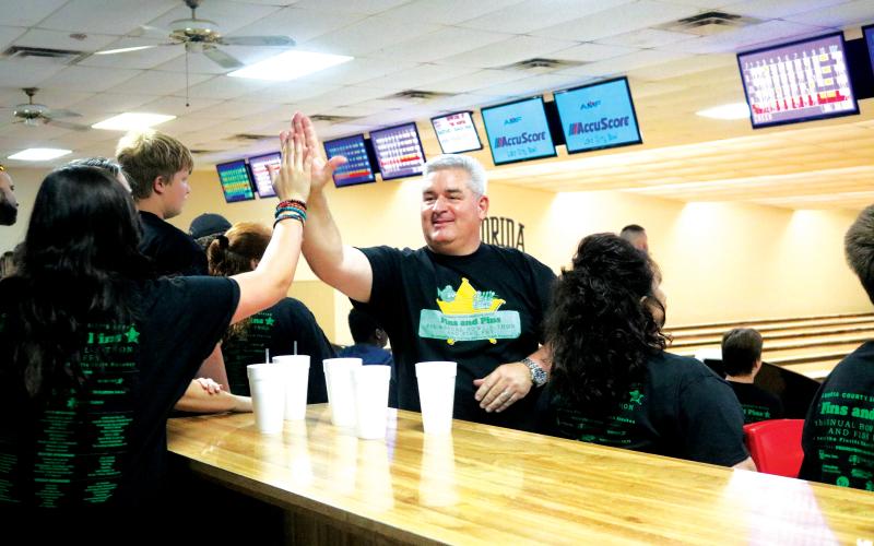 Jesse Stalnaker (right) gives out a high-five during the eighth annual Fins and Pins Bowl-a-Thon in 2019. (FILE)