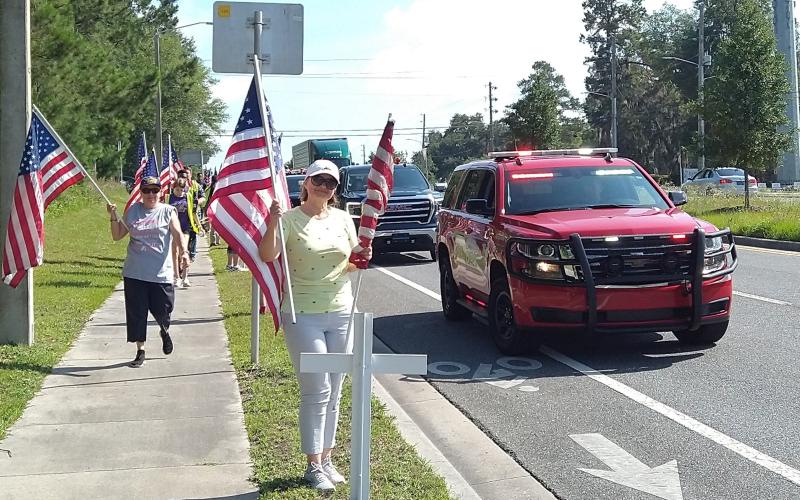 Volunteers, with assistance from the Lake City Fire Department, erect the crosses and flags alongside State Road 47 Saturday morning for the America’s Heroes Program. (COURTESY)