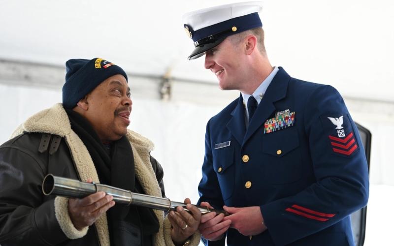 Lake City’s Marvin Deyampert, the eldest nephew of Warren T. Deyampert, presents a long glass to Petty Officer First Class Thomas Broderick of the Coast Guard Cutter Warren Deyampert (WPC-1151) during the commissioning ceremony in Boston on March 30. (Petty Officer 2nd Class Ryan L. Noel/U.S. Coast Guard)