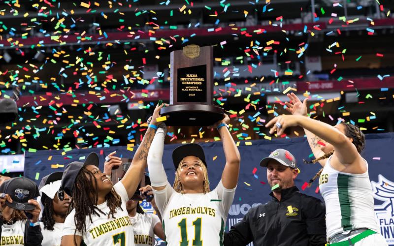 FGC’s Makenzie Phillian lifts the NJCAA championship trophy alongside Klaudia Taylor (7) and head coach Ricky Hufty after the Timberwolves won the inaugural NJCAA title on Saturday at Mercedes-Benz Stadium in Atlanta. (COURTESY OF NFL FLAG)