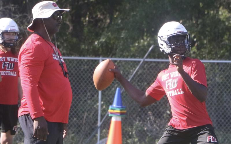 Fort White quarterback Jayden Jackson throws a pass next to head coach Demetric Jackson during Monday’s practice. (MORGAN MCMULLEN/Lake City Reporter)