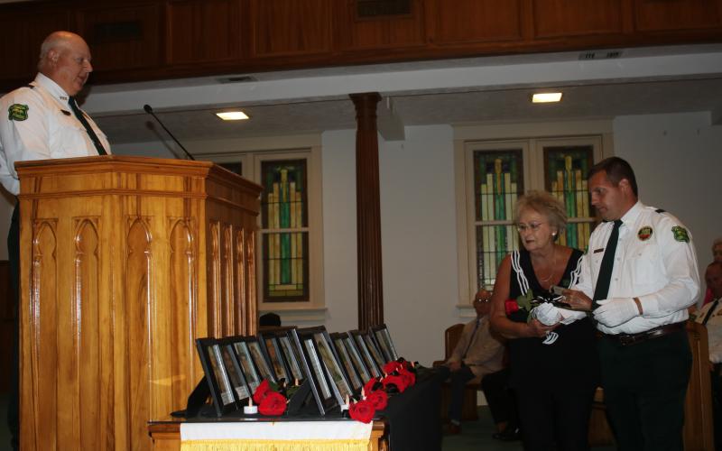 Mollie Burch, the mother of fallen Florida Forest Service Ranger Josh Burch, was escorted by Forest Ranger Ryan Rehberg to place a rose in honor of her son during Tuesday’s Public Safety Memorial service at First Baptist Church. (TONY BRITT/Lake City Reporter)