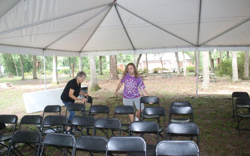Volunteers Joan Alderman (left) and David Enfinger set up chairs beneath a tent at one of the stages for the Florida Folk Festival on Wednesday. (TONY BRITT/Lake City Reporter)