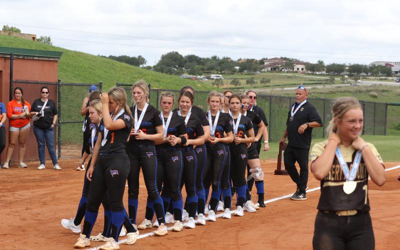 Branford's softball team stands with their runner-up medals while watching Liberty County receive its Class 1A state championship medals on Wednesday at Legends Way Ballfields in Clermont. (MORGAN MCMULLEN/Lake City Reporter)
