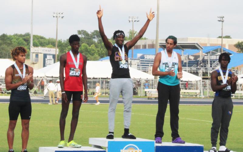 Columbia’s Seth Stockton celebrates on the podium after winning the class 3A state title in the triple jump on Friday. (COURTESY)