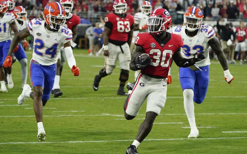 Georgia running back Daijun Edwards runs for a 22-yard touchdown past Florida cornerback Avery Helm (24) and defensive lineman Princely Umanmielen (33) during last season's 'Cocktail Party' on Oct. 29, 2022, in Jacksonville. (JOHN RAOUX/Associated Press)