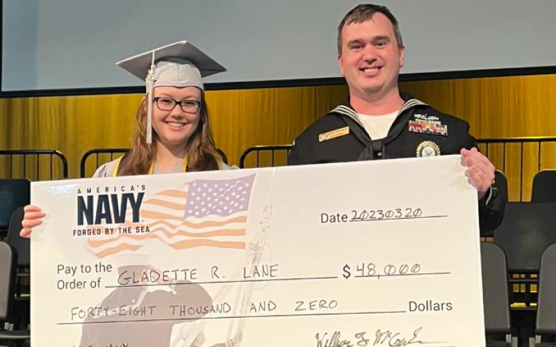 GM1 (SW) William McCracken presents Suwannee Virtual School graduate Gladette Lane with a symbolic signing bonus check for $48,000 from the United States Navy on Friday. (COURTESY)