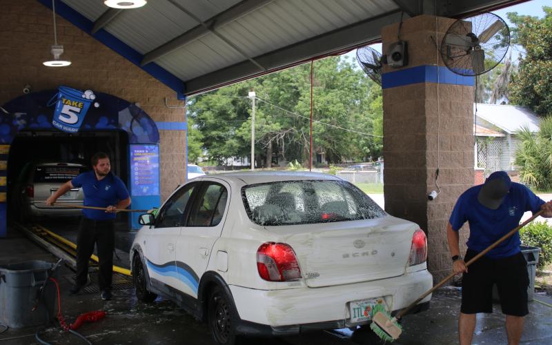Ronald Morris (from left) and Dillon Geiger, Take 5 Car Wash general manager, prep a car with a washing session on Wednesday morning. (TONY BRITT/Lake City Reporter)