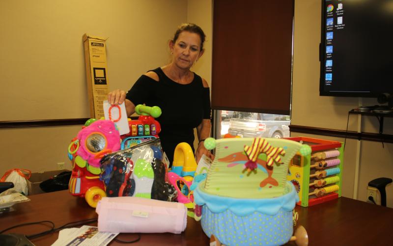 United Way of Suwannee Valley Executive Director Jennifer Anchors looks over some of the items that the organization will sell at its community yard sale Friday. (TONY BRITT/Lake City Reporter)