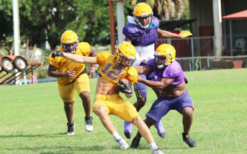 Columbia receiver Camdon Frier is tackled by linebacker Wilson Philemon (right) and safety Jerome Carter during Friday’s scrimmage. (JORDAN KROEGER/Lake City Reporter)