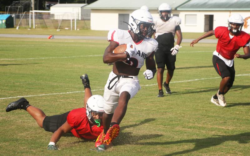 Fort White running back Dakota Fisher runs past linebacker Lecosta Byrd during Friday’s scrimmage. (MORGAN MCMULLEN/Lake City Reporter)