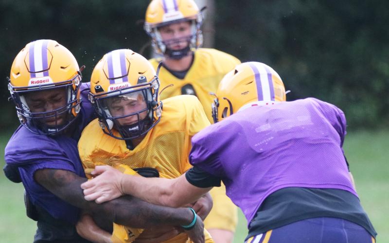Columbia receiver Bynton Edge (middle) is tackled by defensive back Mickell Rivers (left) and defensive end Ayden Phillips (right) after a catch during Tuesday’s practice. (JORDAN KROEGER/Lake City Reporter)