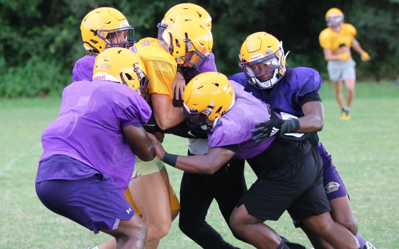 Columbia’s defense swarms to tackle receiver Camdon Frier during Friday’s practice. (JORDAN KROEGER/Lake City Reporter)