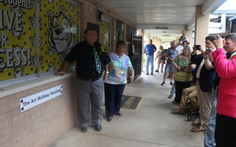 Art Holliday, a former Summers Elementary principal, stands next to the sign for the ‘Art Holliday Building’ at the school on Tuesday. (MORGAN MCMULLEN/Lake City Reporter)