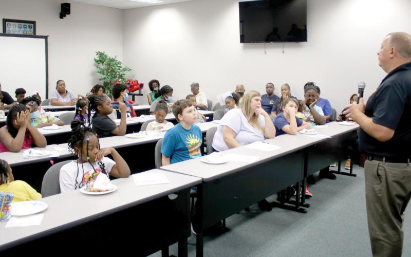 Lake City Police Chief Gerald Butler speaks to a group of more than 35 children on Friday afternoon about the importance of staying in school. (TONY BRITT/Lake City Reporter)