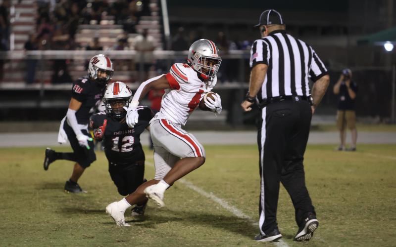 Williston running back Jace McDonald runs past Fort White defensive back Najeeb Smith on Friday. (PAUL BUCHANAN/Special to the Reporter)
