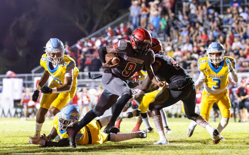 Lafayette quarterback Tywan Williamson leaves a pair of Chiefland defenders behind him on a touchdown run Friday night at Dale Walker Field. (JACK HOWDESHELL/Special to the Reporter)