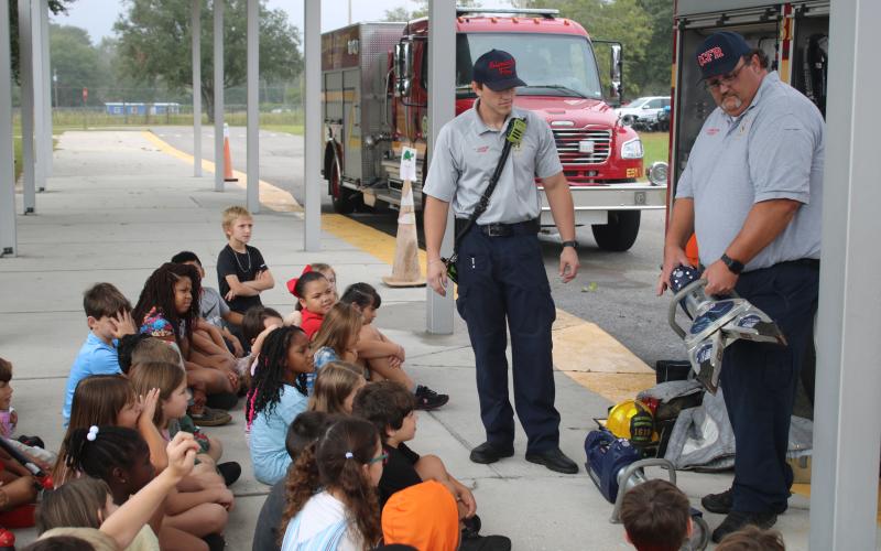 Tyler Vickery (left) and Cody Bertram, Columbia County Fire Rescue firefighters, demonstrate the Hurst Jaws of Life for Westside Elementary School second grade students for Fire Prevention Month. (TONY BRITT/Lake City Reporter)