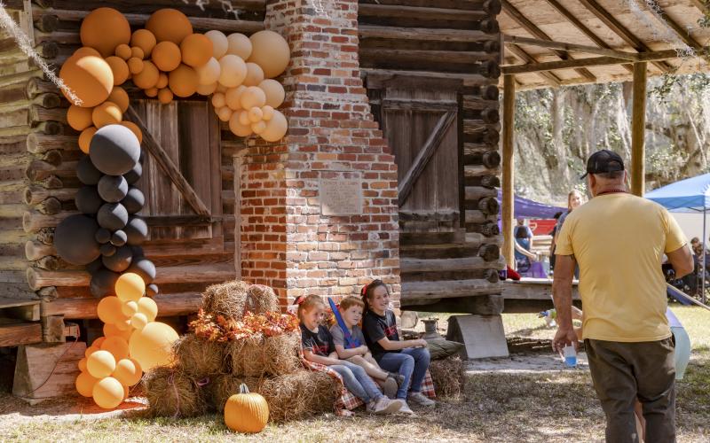 Children pose for a picture in front of the Pioneer Log Cabin in Veterans Memorial Park in Mayo during last year’s Pioneer Day. (FILE)