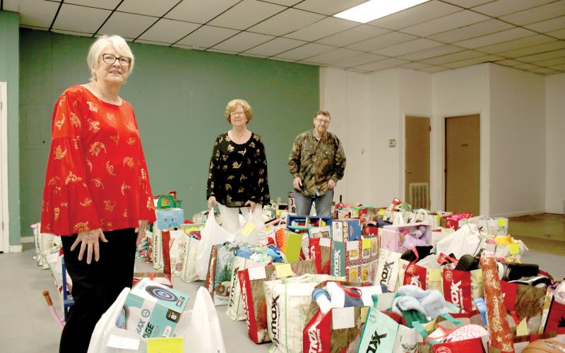 Meally Jenkins (from left), Christmas Dream Machine founder and director, stands amid bags of gifts with volunteers Janet Stanford and Chad Brown on Wednesday afternoon. The Christmas Dream Machine served 616 children this Christmas and was distributing the final bags to families on Wednesday afternoon. (TONY BRITT/Lake City Reporter)