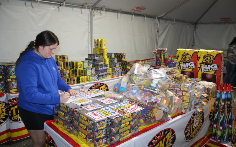 Rorie Lee, a Columbia FFA student, writes a list of prices for the fireworks tent. (TONY BRITT/Lake City Reporter)