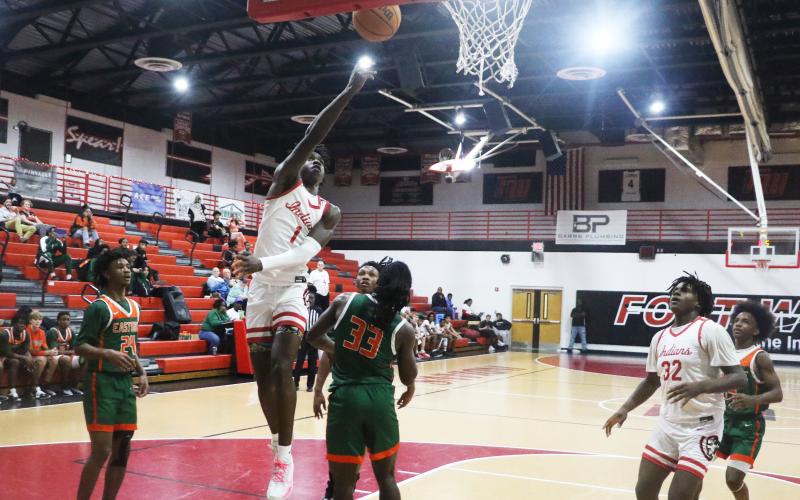 Fort White guard Jayden Jackson makes a layup over Eastside forward Davion Pugh on Friday night. (MORGAN MCMULLEN/Lake City Reporter)